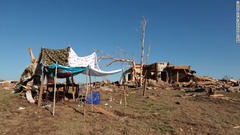 竜巻で破壊された家（右）の横に作られた即席の「避難所」