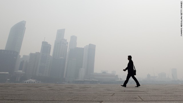 煙に包まれたシンガポールの街中を行く男性。シンガポール以外にも被害が出ている