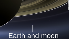 地球は土星の右下、外側の薄い輪の上に、小さな青い点として写っている