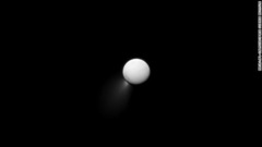 土星の反射光に照らされるエンケラドス。南極からは氷などを吹き上げる＝NASA/JPL/SPACE SCIENCE INSTITUTE提供