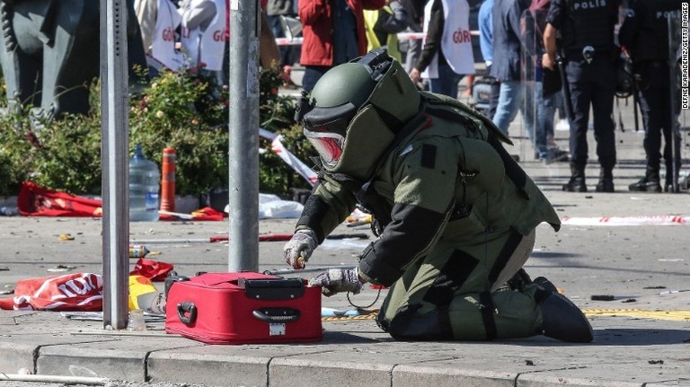 爆発現場のスーツケースを調べる爆弾処理班