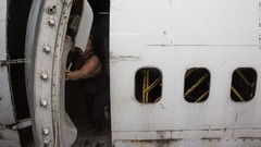 廃棄されたジェット機内の自分の部屋のドアを開ける年配の女性。タイはここ数年高い経済成長を続けているが、富裕層と貧困層の格差は依然として大きい