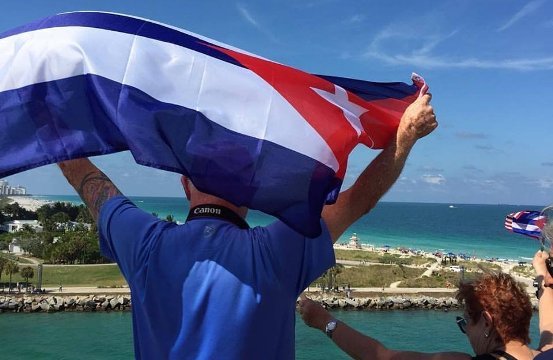 船上でキューバ国旗を掲げるクルーズ船の乗客