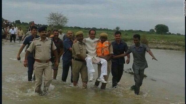 警官に抱えてもらって泥流の中を移動する印マディヤプラデシュ州の州首相