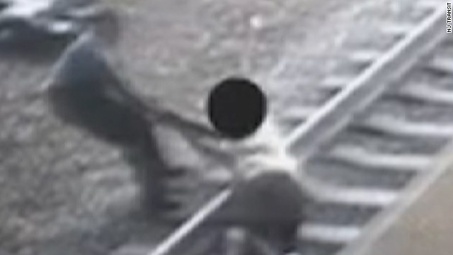 男性の腕をつかみ、線路上から引きずり出す交通警官の映像