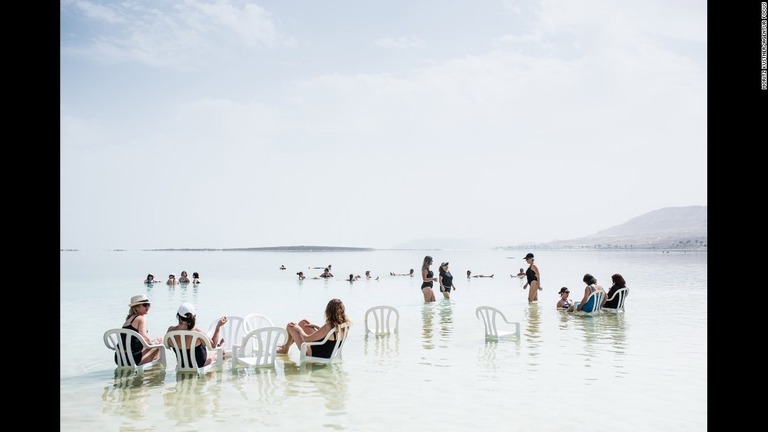 椅子を持ち込み、死海の水の中でくつろぐ観光客