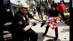 ２月２７日：米カリフォルニア州の集会で米国旗をめぐり争う白人至上主義団体「クー・クラックス・クラン（ＫＫＫ）」のメンバーと男性