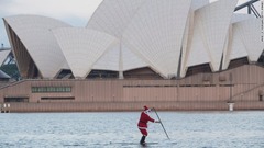 サンタの姿でパドルボードをする男性＝オーストラリア