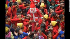 サンタに扮した人物からお菓子を受け取るインドの子どもたち