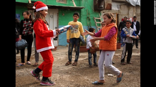 サンタに扮したレバノンの少女がシリア難民の女の子にプレゼントを贈るところ＝ベイルート北部