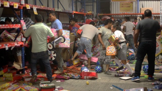 抗議活動に乗じて商店から玩具を持ち去ろうとする人々