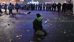 警官隊の近くで地面に座るデモ参加者