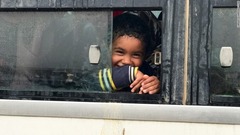 母親らと一緒に難民キャンプへ移送される前、笑顔を見せる少年