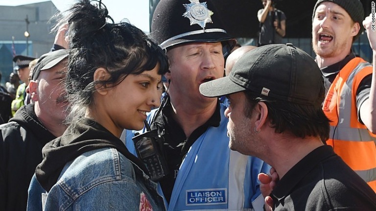 警察官の前で向き合うサフィヤ・カーンさん（左）と極右団体支持の男性