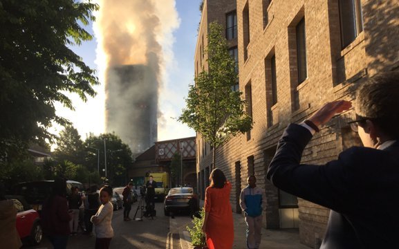 白い煙に包まれた建物を見つめる人々