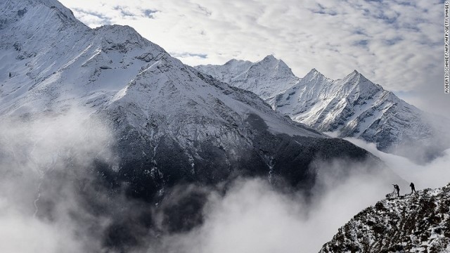 崖の上からエベレストの絶景を眺める登山者たち