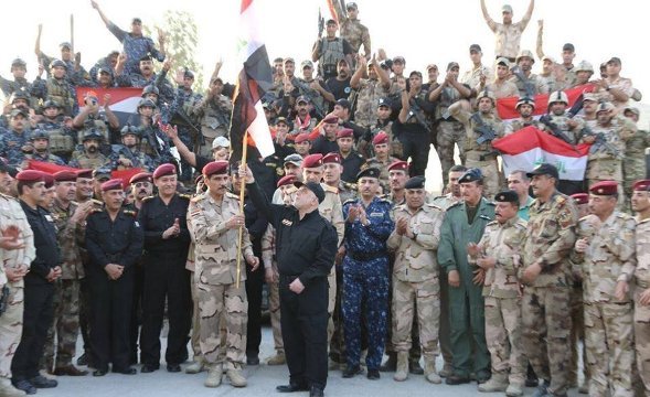 イラク国旗を手に、モスルの完全な解放を宣言するアバディ首相（中央）
