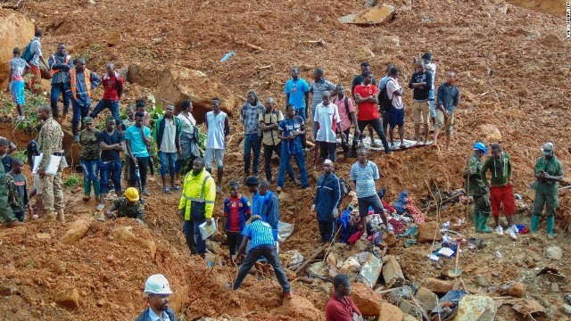 土砂崩れの現場に立つ住民とレスキュー隊員ら