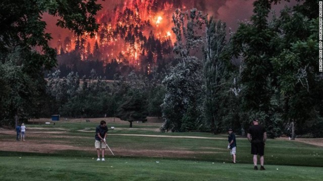 背後に迫る山火事も意に介さずプレーを続けるゴルファーたち