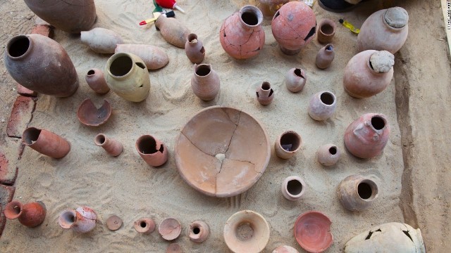 陶器の破片を集め、埋葬物を復元する