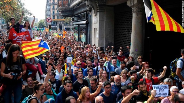 官庁の建物の外でカタルーニャの旗を掲げるデモ隊