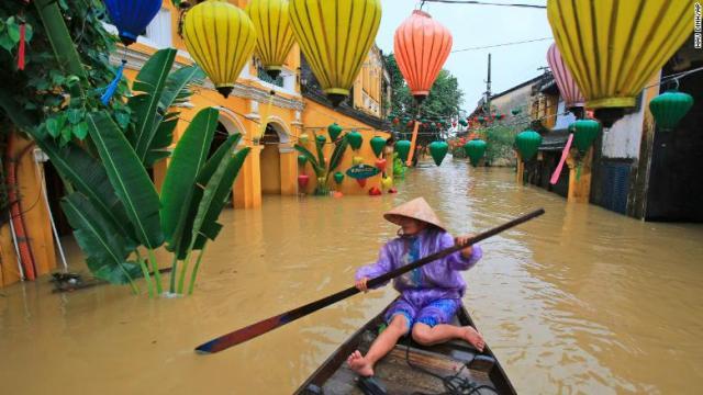 冠水したベトナム中部の都市ホイアンの通りを舟で移動する住民