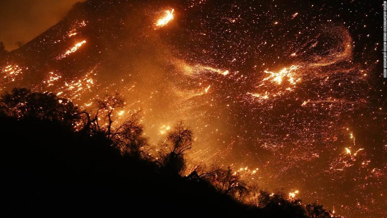 ロサンゼルス郊外のシャドーヒルズ地区の丘の中腹を火の粉が舞う＝５日
