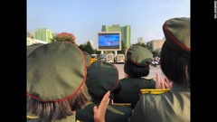 北朝鮮のテレビがミサイル発射の映像を流すなか、拍手をする群衆＝８月３０日、平壌駅近く