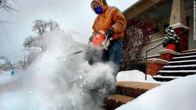 イリノイ州ブルーミングトンで家の階段の雪かきをする男性