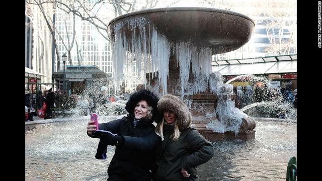 ニューヨーク市で噴水のつららを背景に自撮りする女性ら