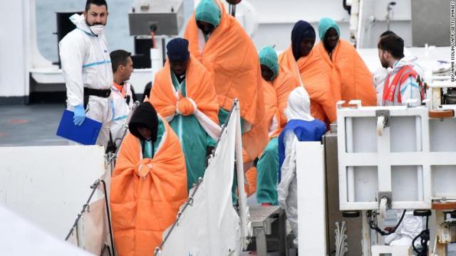 イタリア沿岸警備隊の船から降りる難民ら