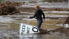 泥水のあふれる小川を渡る男性
