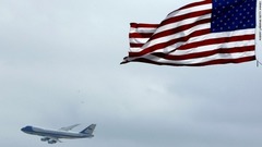 国旗の向こうに空を行くエアフォースワンが見える＝２００４年、米フロリダ州