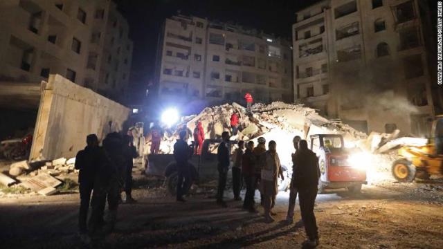 空爆を受け倒壊した建物のがれきの中で、救助隊が生き埋めになった家族の捜索に当たっている＝４日、イドリブ