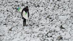北東イングランドのレッドカーで凍った岩の上を歩くサーファー