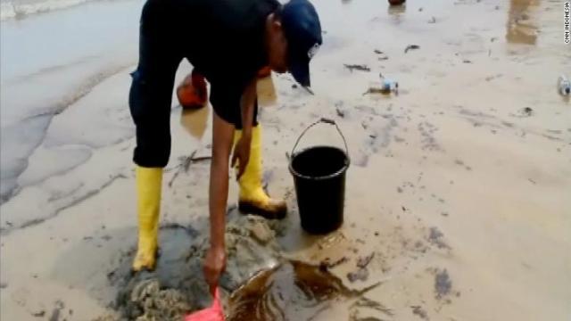 インドネシア・カリマンタン島の海岸で流出した油を除去する作業員