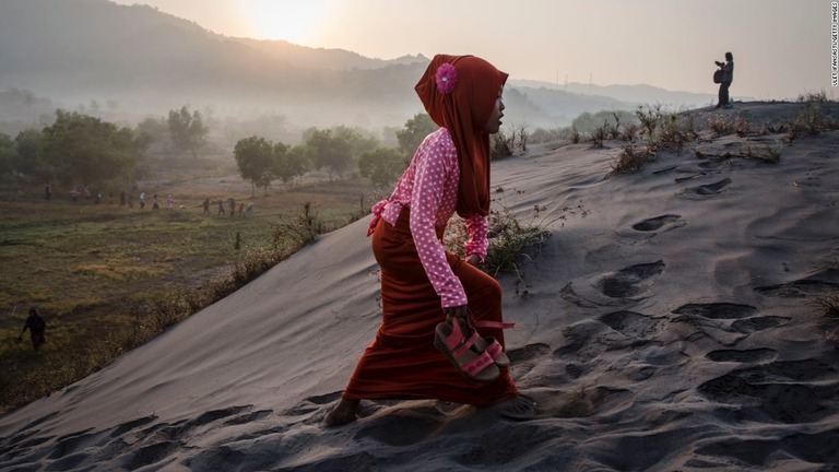 祈りを行うために砂地を歩くイスラム教徒の女性