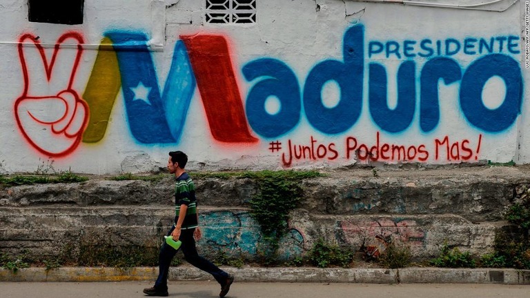 再選を果たしたマドゥロ大統領を支持する落書きの前を横切る男性