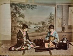 伝統的な家財道具に囲まれて縫い物をする女性２人。持ち運び可能な火鉢は小たんすが備えられ、やかんを沸かすこともできる。奥には掛け軸も＝Kusakabe Kimbei