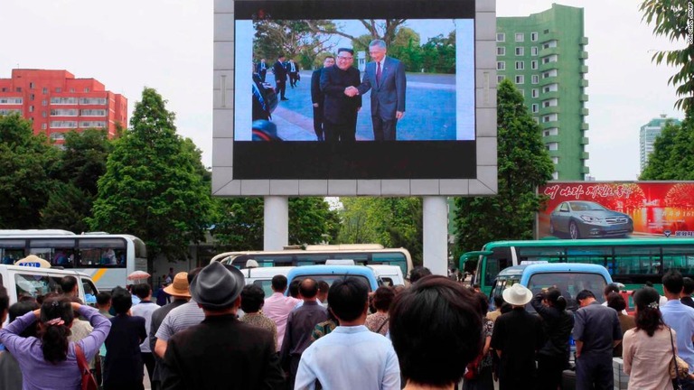 駅の外にある巨大スクリーンで流れるニュースを見る北朝鮮の人々＝平壌