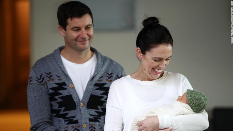 眠る赤ちゃんを抱いて病院から出てくるアーダーン首相（右）と夫のゲイフォードさん