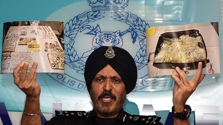 ナジブ前首相の関係先から押収した宝石類などの写真を掲げるマレーシア警察の警察官