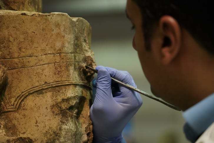 大エジプト博物館の保全センターで太陽神ラーの像に向き合う修復の専門家