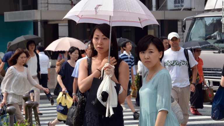 強い日差しを避けるため日傘をさす歩行者＝１２日、東京/YOSHIKAZU TSUNO/AFP/AFP/Getty Images