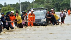 ダムからの水が村にあふれ、冠水した道路を進む住民ら