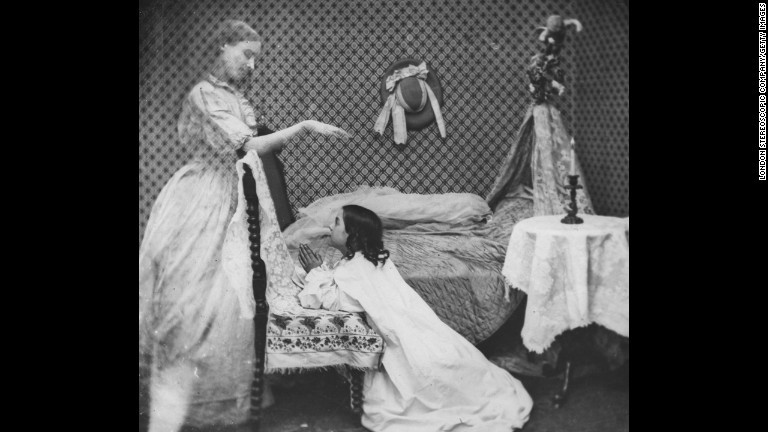 ベッドサイドで祈る少女の前に女性の幽霊が出現/London Stereoscopic Company/Getty Images