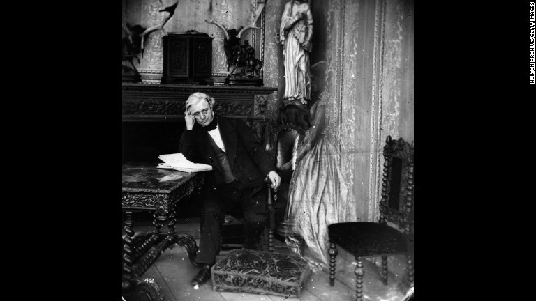 居間で読書する男性のもとに幽霊が訪れている/Hulton Archive/Getty Images