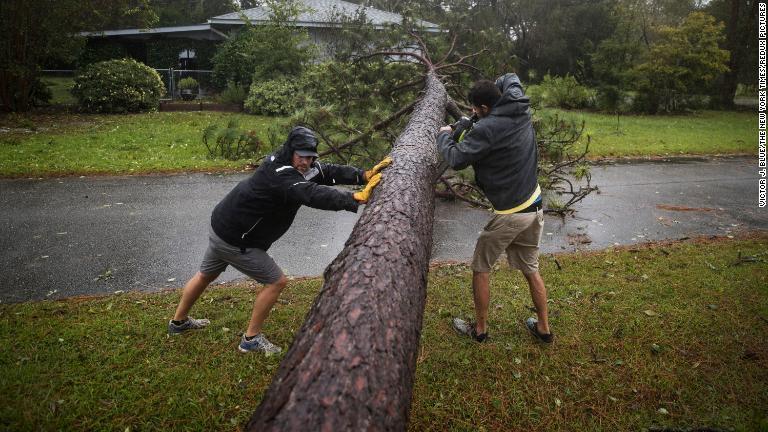道路をふさいだ木をチェーンソーで切る住民＝１４日、ノースカロライナ州ウィルミントン/Victor J. Blue/The New York Times/Redux Pictures