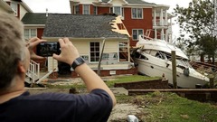 ガレージに突っ込んだボートの写真を撮る人＝１５日、ノースカロライナ州ニューバーン