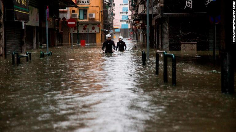 冠水した道路を進む救急隊員＝１６日、マカオ/Isaac Lawrence/AFP/Getty Images